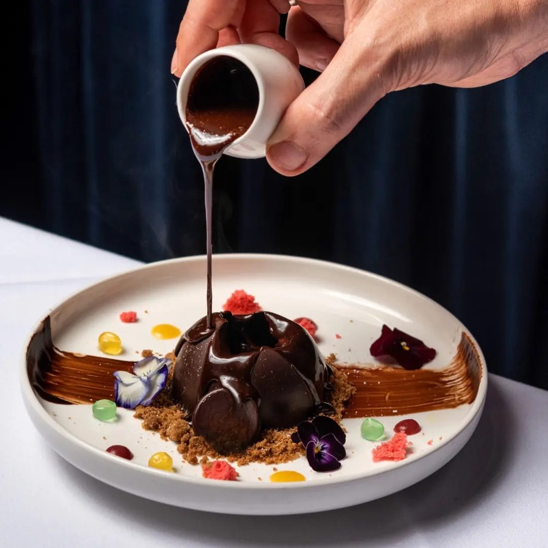 Chocolate dessert with sauce being poured